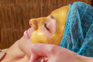 Yüzünde model altın maskesi uygulama. Kozmetik prosedürler
