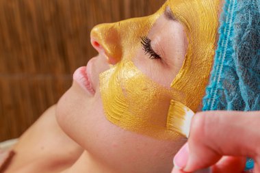 Yüzünde model altın maskesi uygulama. Kozmetik prosedürler