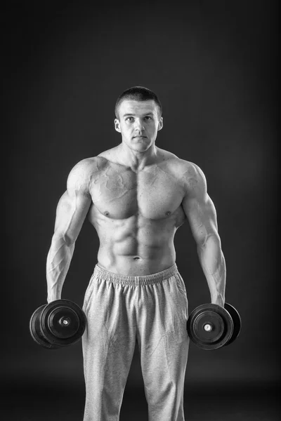 Culturista posando en diferentes poses demostrando sus músculos. Fracaso en un fondo oscuro. Varón mostrando tensión muscular. Hermoso atleta cuerpo muscular . — Foto de Stock