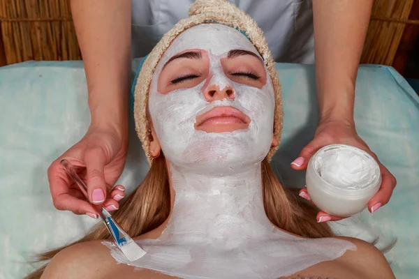 Menina com um esteticista no salão de spa. Esteticista realiza procedimentos cosméticos. Aplicação de creme cosmético. Cosmetologia, facial, beleza - O conceito de cuidados com a pele facial. Artigo sobre cosmetologia . — Fotografia de Stock