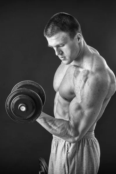 Bodybuilder poserar i olika poser visar sina muskler. Fel på en mörk bakgrund. Manliga visar musklerna spännare. Vackra muskulös kropp idrottsman nen. — Stockfoto