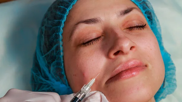 Cosmetic injection in the spa salon. Beautician makes injection into the patient's face. — Stock Photo, Image