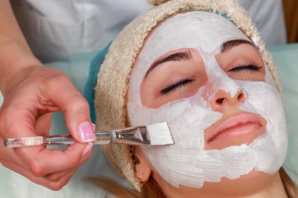 Girl with a beautician at spa salon. Beautician performs cosmetic procedures.applying cosmetic cream. Cosmetology, facial, beauty - The concept of facial skin care. Article about cosmetology. — Stock Photo, Image