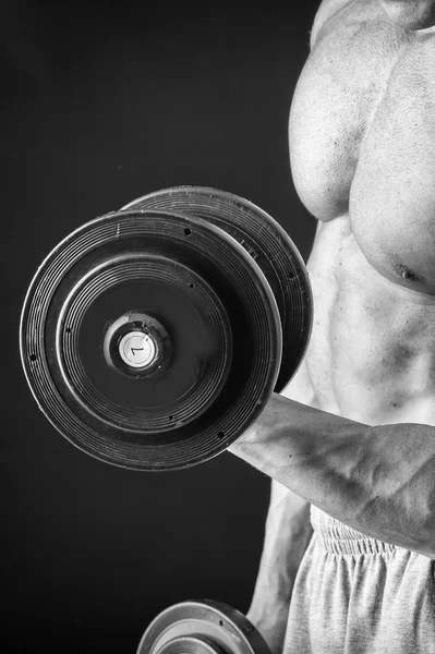 Culturista posa in pose diverse dimostrando i loro muscoli. Fallimento su uno sfondo scuro. Maschio che mostra tensione muscolare. Bellissimo atleta del corpo muscolare . — Foto Stock