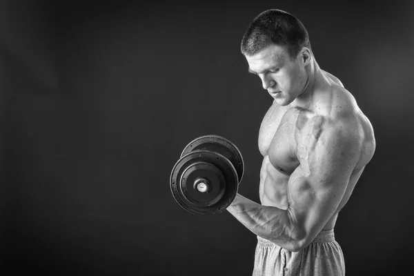 Culturista posa in pose diverse dimostrando i loro muscoli. Fallimento su uno sfondo scuro. Maschio che mostra tensione muscolare. Bellissimo atleta del corpo muscolare . — Foto Stock