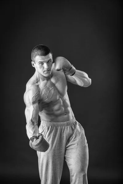 El hombre con guantes de boxeo. Joven boxeador sobre fondo negro. Boxeador listo para pelear. Boxeo, entrenamiento, músculo, fuerza, poder - el concepto de entrenamiento de fuerza y boxeo —  Fotos de Stock