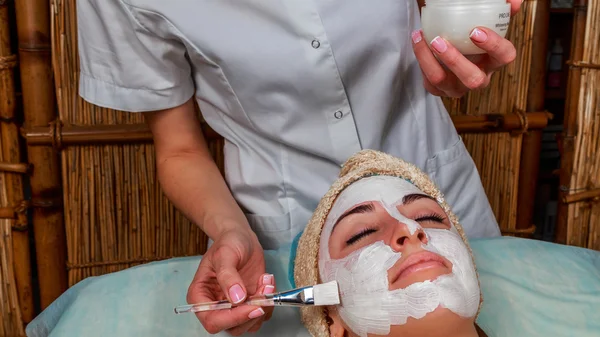 Chica con una esteticista en el salón de spa. esteticista realiza procedimientos cosméticos. Aplicación de crema cosmética. Cosmetología, facial, belleza - El concepto de cuidado de la piel facial. Artículo sobre cosmetología . —  Fotos de Stock