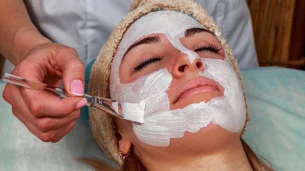 Ragazza con un estetista al centro benessere. Estetista esegue procedure cosmetiche.applicazione di crema cosmetica. Cosmetologia, viso, bellezza - Il concetto di cura della pelle del viso. Articolo sulla cosmetologia . — Foto Stock