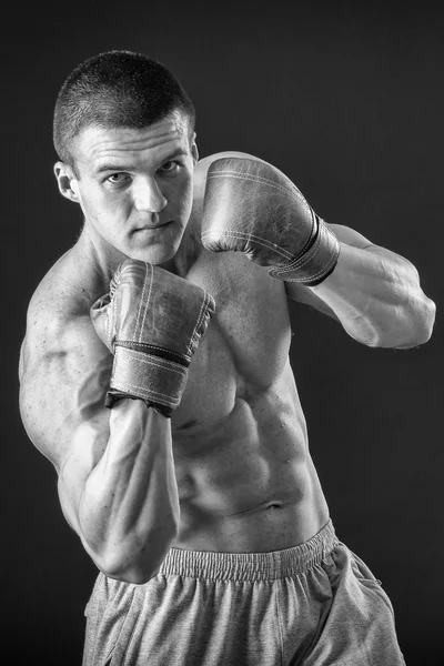 L'uomo con i guanti da boxe. Giovane pugile Boxer su sfondo nero. Boxe pronto a combattere. Boxe, allenamento, muscoli, forza, potenza: il concetto di allenamento della forza e pugilato — Foto Stock