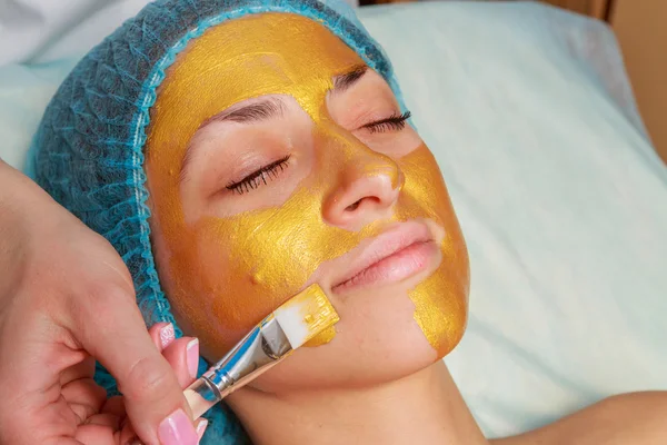 Yüzünde model altın maskesi uygulama. Kozmetik prosedürler
