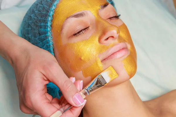 Yüzünde model altın maskesi uygulama. Kozmetik prosedürler