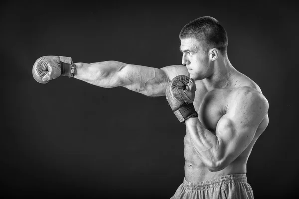 Человек в боксёрских перчатках. Молодой боксёр на чёрном фоне. Боксёр готов к бою. Бокс, тренировки, мышцы, сила, мощь - понятие силовой подготовки и бокса — стоковое фото
