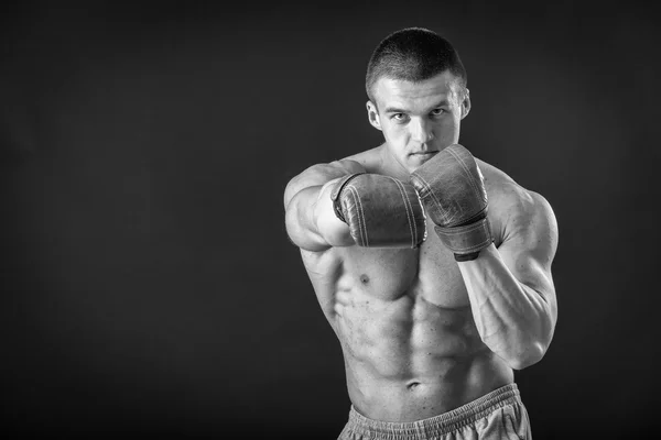 L'uomo con i guanti da boxe. Giovane pugile Boxer su sfondo nero. Boxe pronto a combattere. Boxe, allenamento, muscoli, forza, potenza: il concetto di allenamento della forza e pugilato — Foto Stock