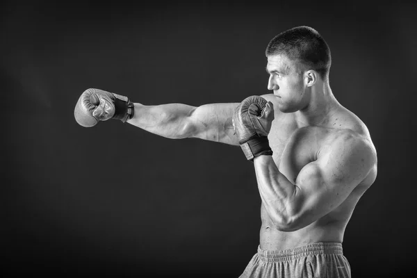 El hombre con guantes de boxeo. Joven boxeador sobre fondo negro. Boxeador listo para pelear. Boxeo, entrenamiento, músculo, fuerza, poder - el concepto de entrenamiento de fuerza y boxeo — Foto de Stock