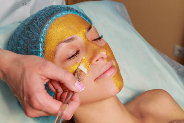 Toepassing van gouden maskers op het gezicht van het model. Cosmetische ingrepen — Stockfoto