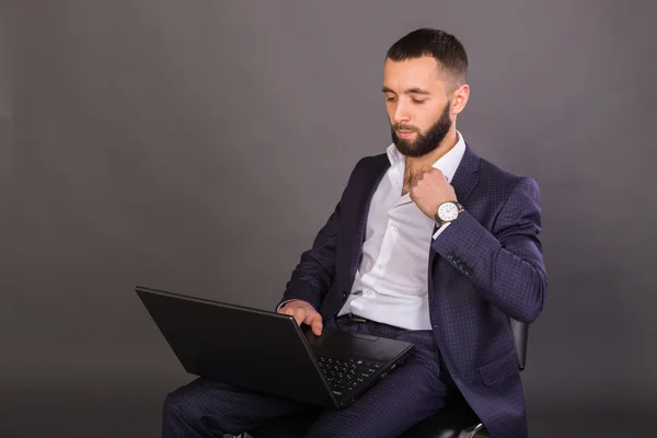 Hombre joven y exitoso en un traje de negocios con un portátil en las manos — Foto de Stock