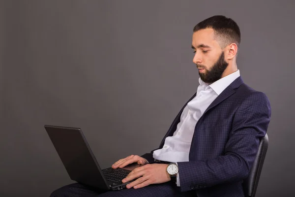 İş elbiseli genç, başarılı adam elinde bir dizüstü bilgisayar ile — Stok fotoğraf