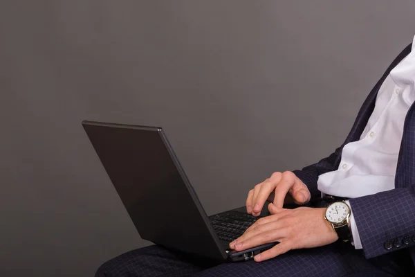 Hombre joven y exitoso en un traje de negocios con un portátil en las manos —  Fotos de Stock