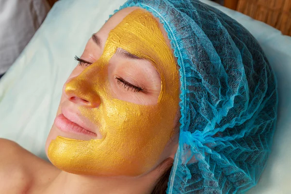 Yüzünde model altın maskesi uygulama. Kozmetik prosedürler