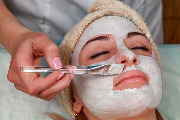 Menina com um esteticista no salão de spa. Esteticista realiza procedimentos cosméticos. Aplicação de creme cosmético. Cosmetologia, facial, beleza - O conceito de cuidados com a pele facial. Artigo sobre cosmetologia . — Fotografia de Stock