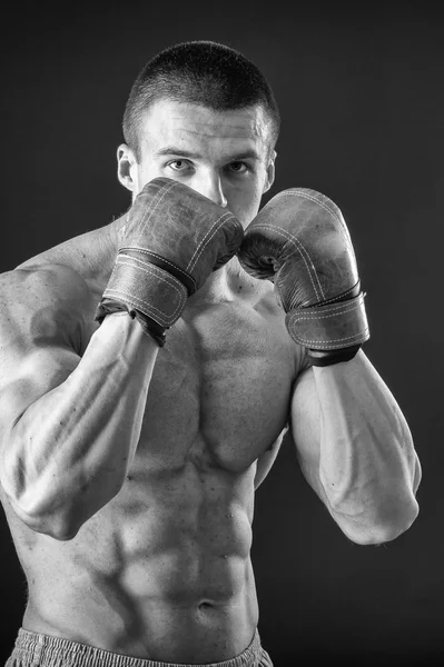 El hombre con guantes de boxeo. Joven boxeador sobre fondo negro. Boxeador listo para pelear. Boxeo, entrenamiento, músculo, fuerza, poder - el concepto de entrenamiento de fuerza y boxeo —  Fotos de Stock
