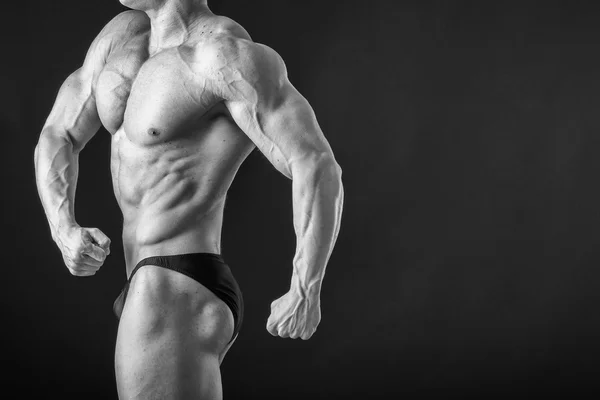 Fisiculturista posando em diferentes poses demonstrando seus músculos. Falha num fundo escuro. Homem mostrando músculos se esforçando. Bonito atleta corpo muscular . — Fotografia de Stock