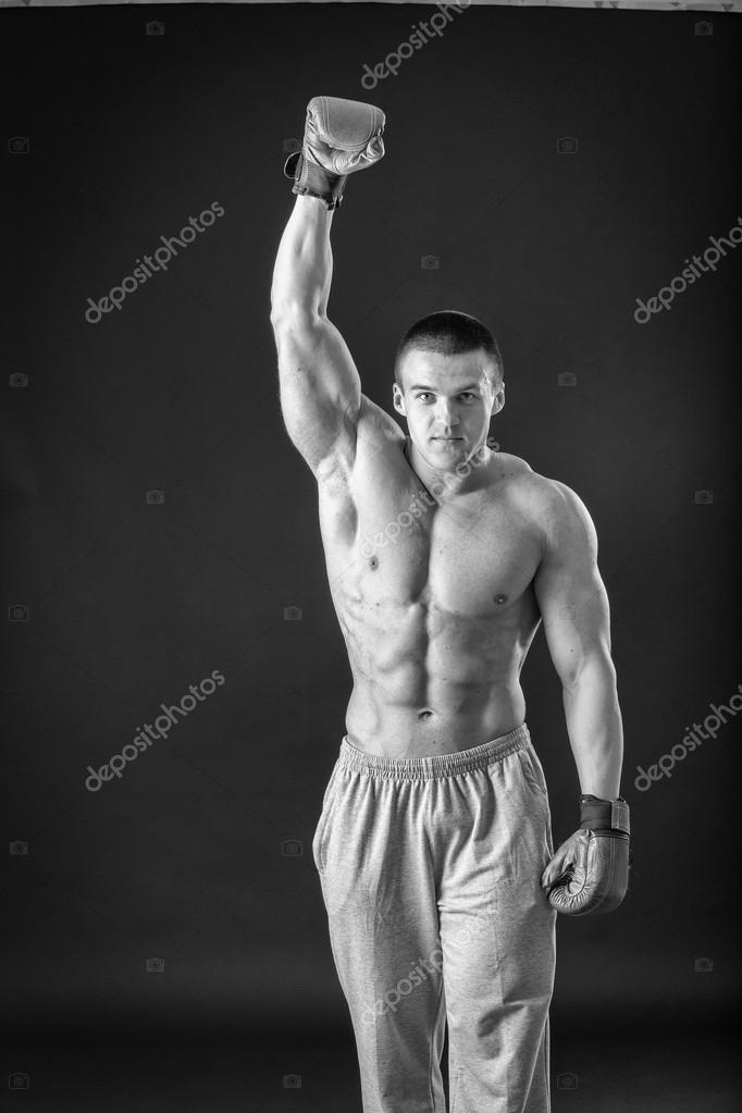 The man in boxing gloves. Young Boxer fighter over black background. Boxing man ready to fight