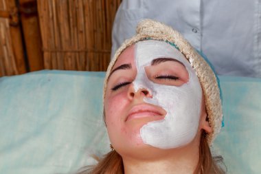 Güzellik salonunda güzellik uzmanı olan bir kız. Güzellik uzmanı kozmetik işlemleri yapıyor. Kozmetik krem uyguluyor. Kozmetoloji, yüz bakımı, güzellik yüz bakımı kavramı. Kozmetoloji hakkında makale.