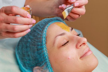 Yüzünde model altın maskesi uygulama. Kozmetik prosedürler