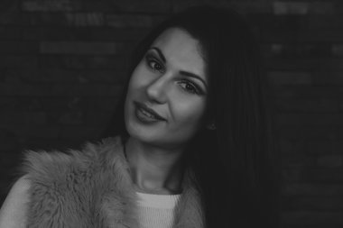 Karanlık bir arka plan üzerinde güzel, gizemli, şirin esmer. Siyah ve beyaz fotoğraf güzel gizemli esmer.