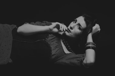 Karanlık bir arka plan üzerinde güzel, gizemli, şirin esmer. Siyah ve beyaz fotoğraf güzel gizemli esmer.