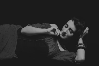 Karanlık bir arka plan üzerinde güzel, gizemli, şirin esmer. Siyah ve beyaz fotoğraf güzel gizemli esmer.