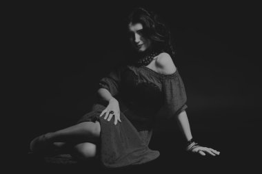 Karanlık bir arka plan üzerinde güzel, gizemli, şirin esmer. Siyah ve beyaz fotoğraf güzel gizemli esmer.