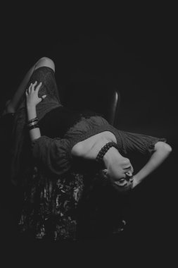 Karanlık bir arka plan üzerinde güzel, gizemli, şirin esmer. Siyah ve beyaz fotoğraf güzel gizemli esmer.