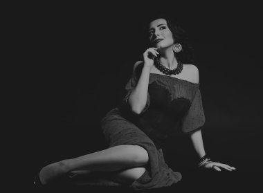 Karanlık bir arka plan üzerinde güzel, gizemli, şirin esmer. Siyah ve beyaz fotoğraf güzel gizemli esmer.