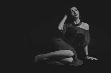 Karanlık bir arka plan üzerinde güzel, gizemli, şirin esmer. Siyah ve beyaz fotoğraf güzel gizemli esmer.