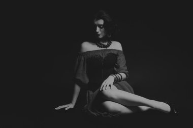 Karanlık bir arka plan üzerinde güzel, gizemli, şirin esmer. Siyah ve beyaz fotoğraf güzel gizemli esmer.