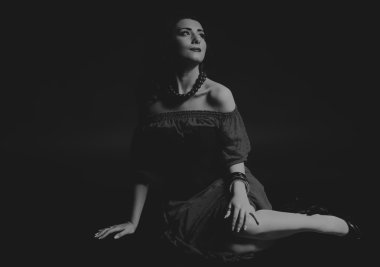 Karanlık bir arka plan üzerinde güzel, gizemli, şirin esmer. Siyah ve beyaz fotoğraf güzel gizemli esmer.