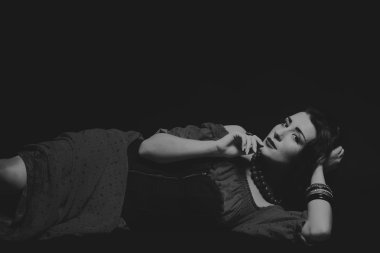 Karanlık bir arka plan üzerinde güzel, gizemli, şirin esmer. Siyah ve beyaz fotoğraf güzel gizemli esmer.