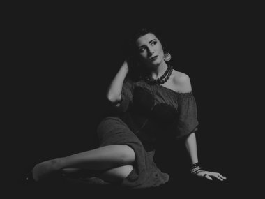 Karanlık bir arka plan üzerinde güzel, gizemli, şirin esmer. Siyah ve beyaz fotoğraf güzel gizemli esmer.