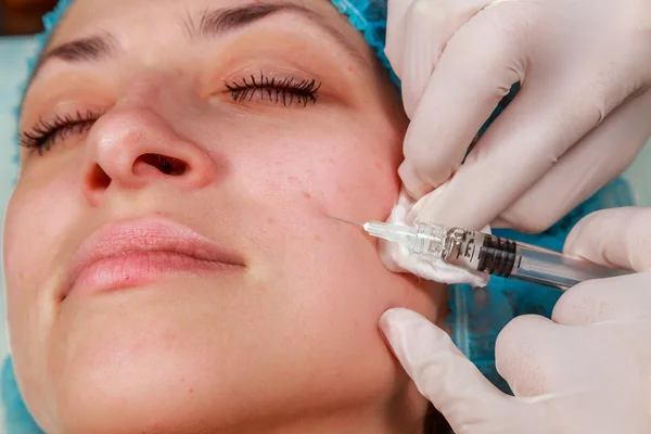 Cosmetic injection in the spa salon. Beautician makes injection into the patient's face. Beauty injections, mesotherapy, revitalization, cosmetic medicine injection - the concept of rejuvenation.