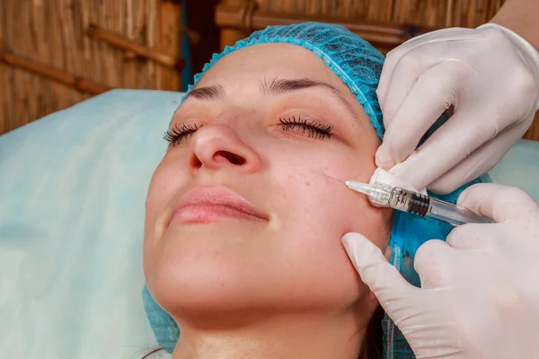 Cosmetic injection in the spa salon. Beautician makes injection into the patient's face. Beauty injections, mesotherapy, revitalization, cosmetic medicine injection - the concept of rejuvenation.