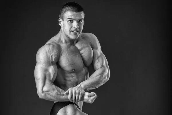 Culturista posando en diferentes poses demostrando sus músculos. Fracaso en un fondo oscuro. Varón mostrando tensión muscular. Hermoso atleta cuerpo muscular . —  Fotos de Stock