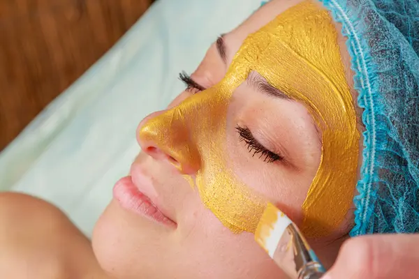 Tillämpning av gyllene masker på modellen. Kosmetiska behandlingar — Stockfoto