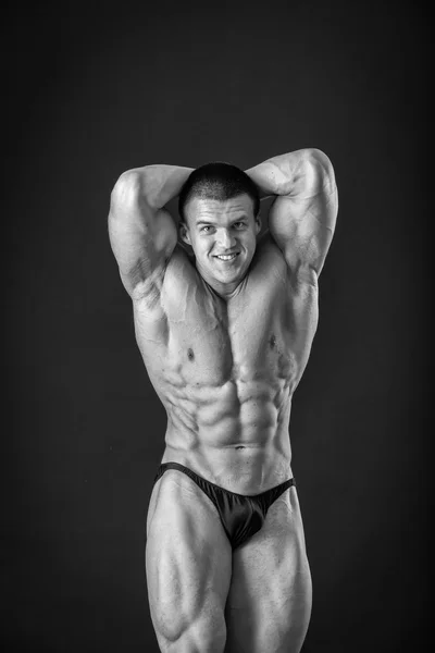 Bodybuilder posant dans différentes poses démontrant leurs muscles. Échec sur fond sombre. Homme montrant des muscles tendus. Magnifique athlète du corps musculaire . — Photo