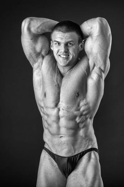 Bodybuilder posing in different poses demonstrating their muscles. Failure on a dark background. Male showing muscles straining. Beautiful muscular body athlete. — Stock Photo, Image