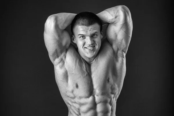 Fisiculturista posando em diferentes poses demonstrando seus músculos. Falha num fundo escuro. Homem mostrando músculos se esforçando. Bonito atleta corpo muscular . — Fotografia de Stock