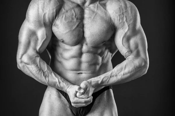 Fisiculturista posando em diferentes poses demonstrando seus músculos. Falha num fundo escuro. Homem mostrando músculos se esforçando. Bonito atleta corpo muscular . — Fotografia de Stock