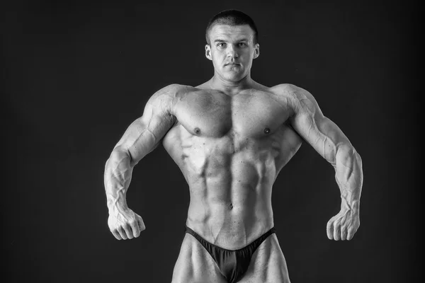 Fisiculturista posando em diferentes poses demonstrando seus músculos. Falha num fundo escuro. Homem mostrando músculos se esforçando. Bonito atleta corpo muscular . — Fotografia de Stock