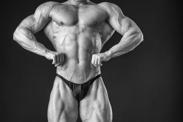 Bodybuilder poserar i olika poser visar sina muskler. Fel på en mörk bakgrund. Manliga visar musklerna spännare. Vackra muskulös kropp idrottsman nen. — Stockfoto